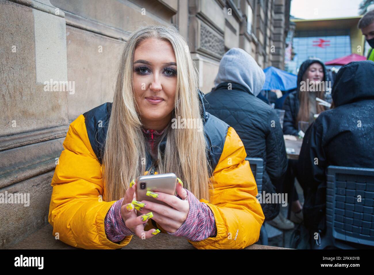 Junge Frau mit langen, gepflegten Acryl-Nägeln mit Mobiltelefon in Glasgow, Schottland Stockfoto