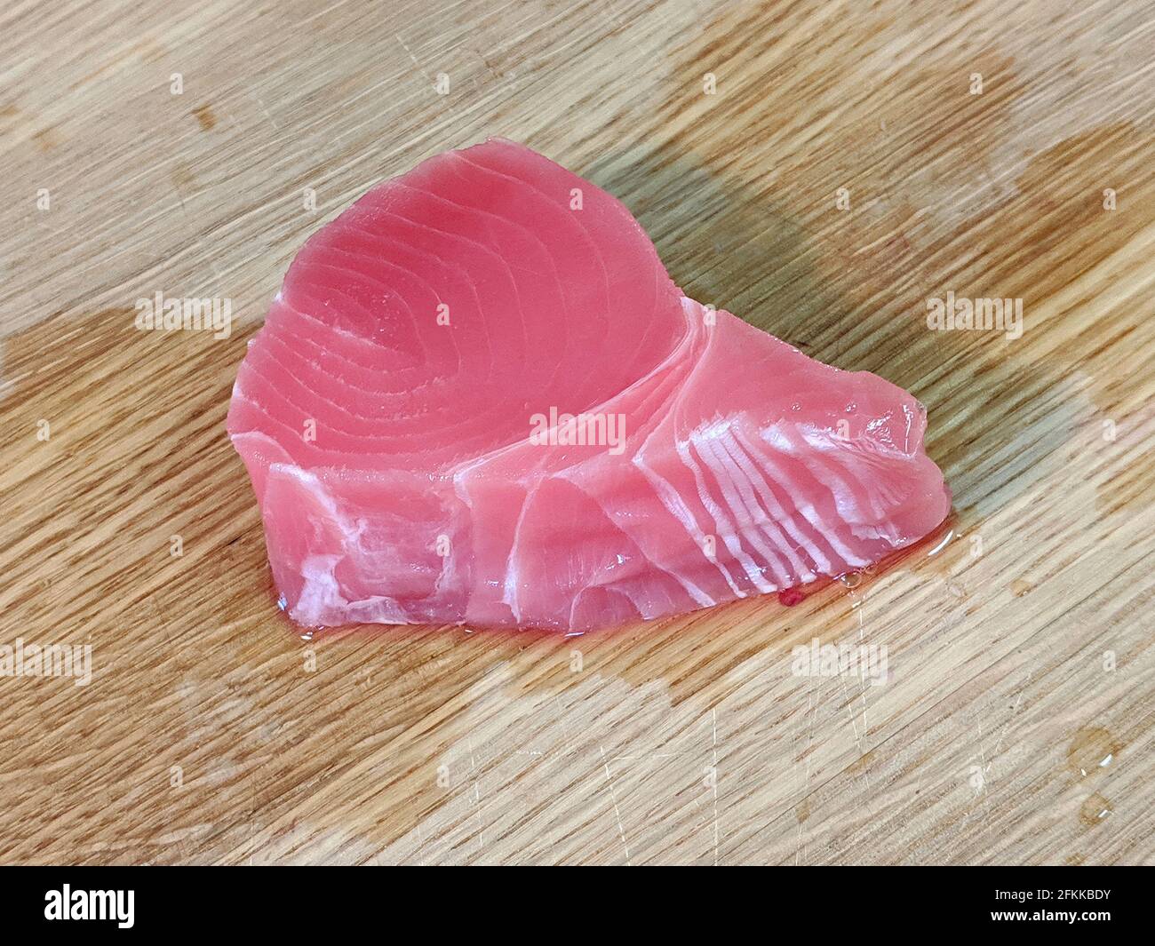 Frisches, rosafarbenes Ahi-Thunfischfilet unverpackt auf einem hölzernen Bambusschneidebrett Stockfoto