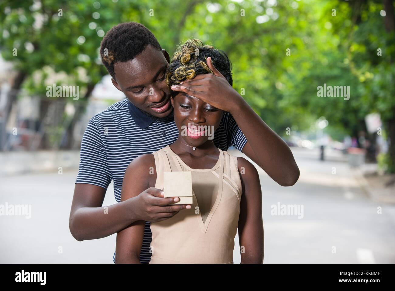 Ein verliebtes Paar, das auf der Straße ging, überraschte ihn, indem er seiner Freundin einen Ring anbot. Stockfoto