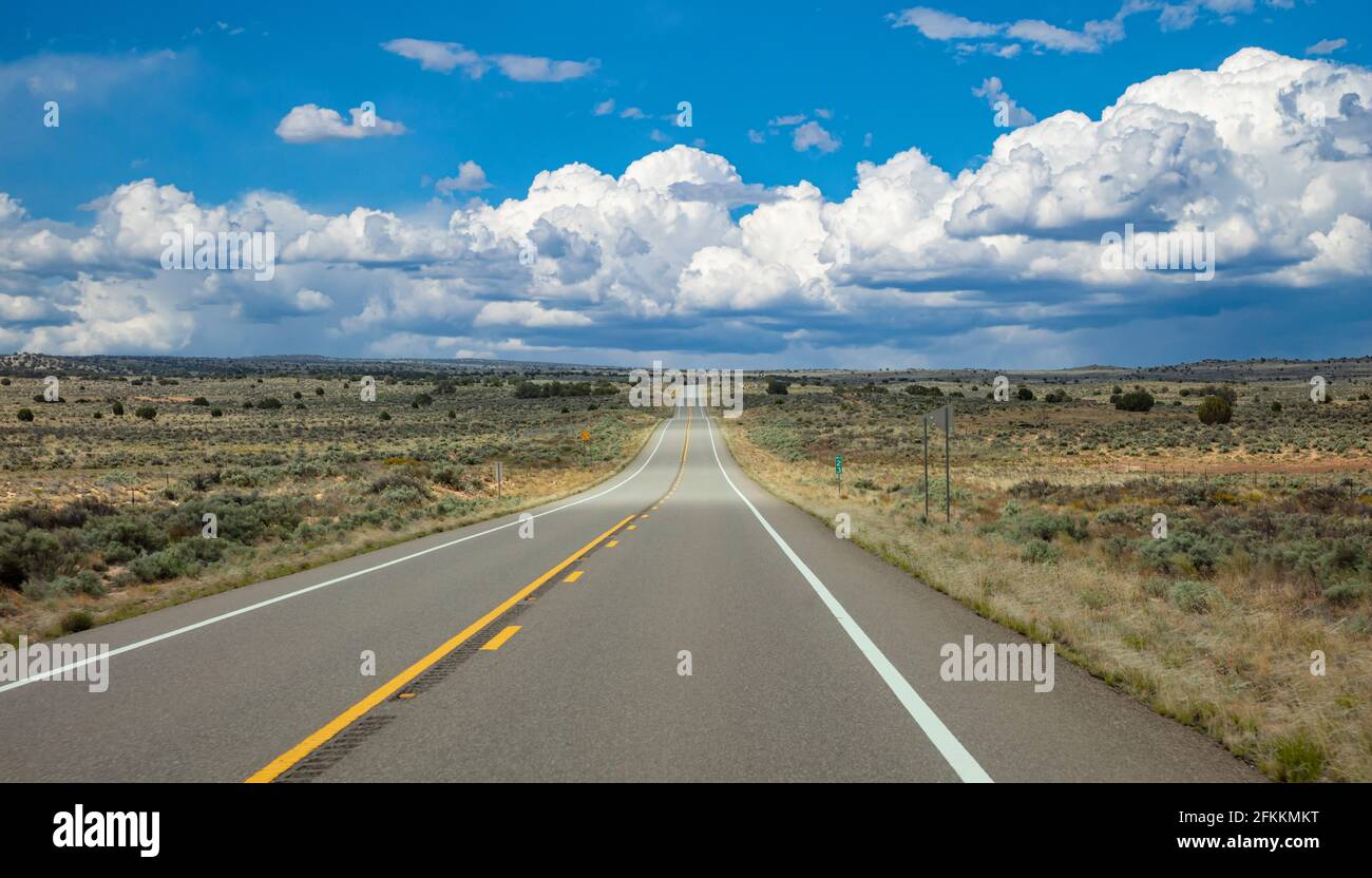 Autobahn an einem sonnigen Frühlingstag, Land USA. Leere Nationalstraße mit Höhen und Tiefen, die durch die amerikanische Wüste führt, blauer, wolkiger Himmel im Hintergrund Stockfoto