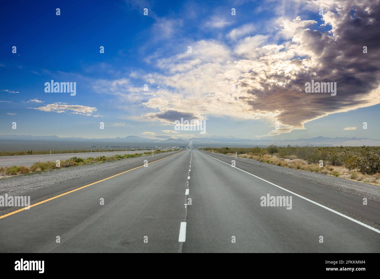 Autobahn an einem sonnigen Frühlingstag, Land USA. Leere Nationalstraße geradeaus, durch die amerikanische Wüste, blauer, wolkiger Himmel im Hintergrund Stockfoto