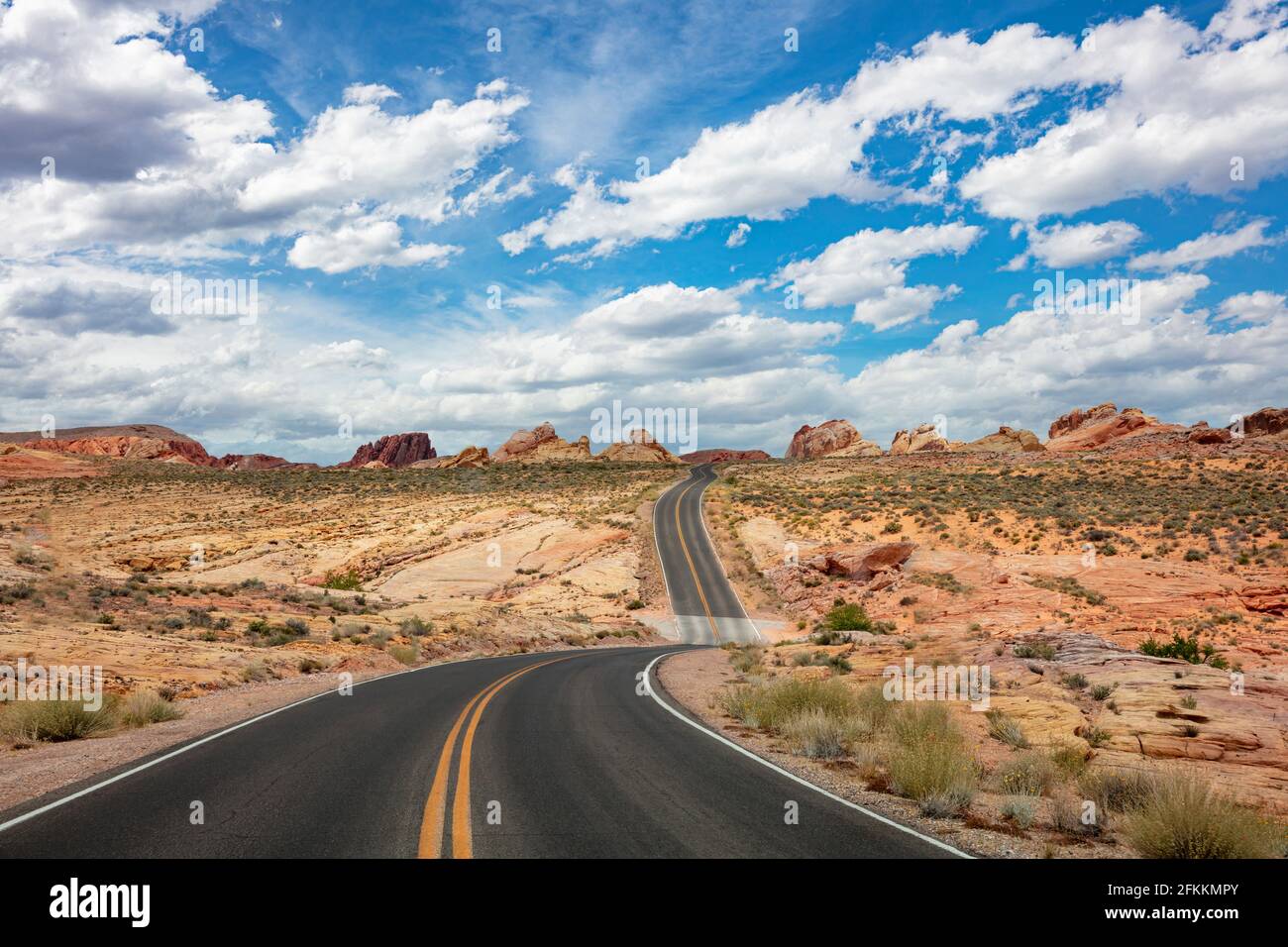 Valley of Fire State Park, Nevada, USA, leere malerische Asphaltstraße an einem sonnigen Frühlingstag, blauer, wolkiger Himmel im Hintergrund Stockfoto