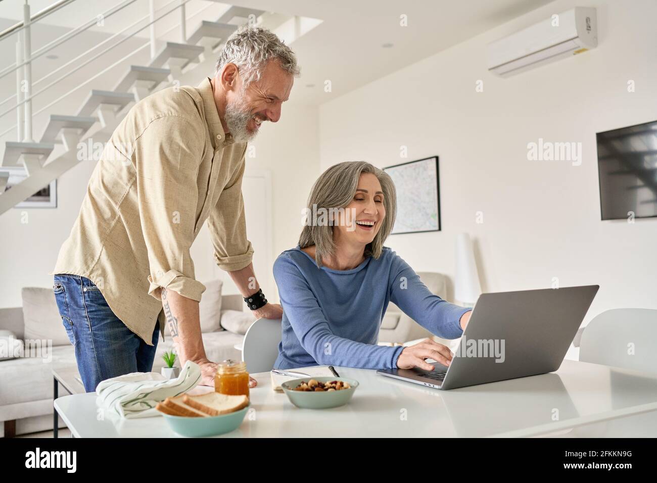 Glückliches Paar mittleren Alters, das Spaß mit Laptop-Computer zu Hause hat. Stockfoto