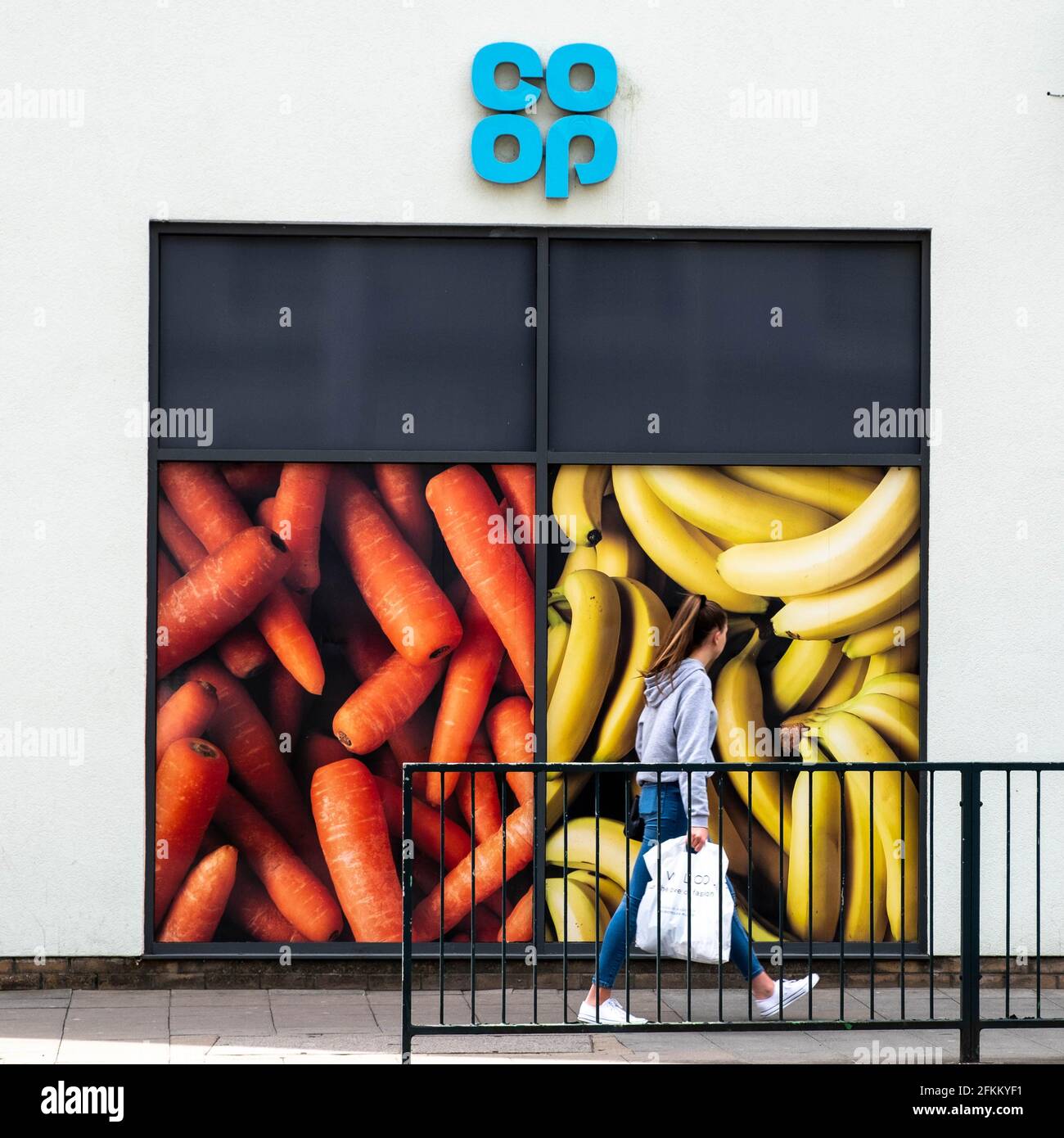 Epsom Surrey London, Großbritannien, Mai 02 2021, Frau, die an EINEM Co-op- oder Cooperative Retail Supermarket-Werbetafel mit EINEM Einkaufstasche vorbeigeht Stockfoto