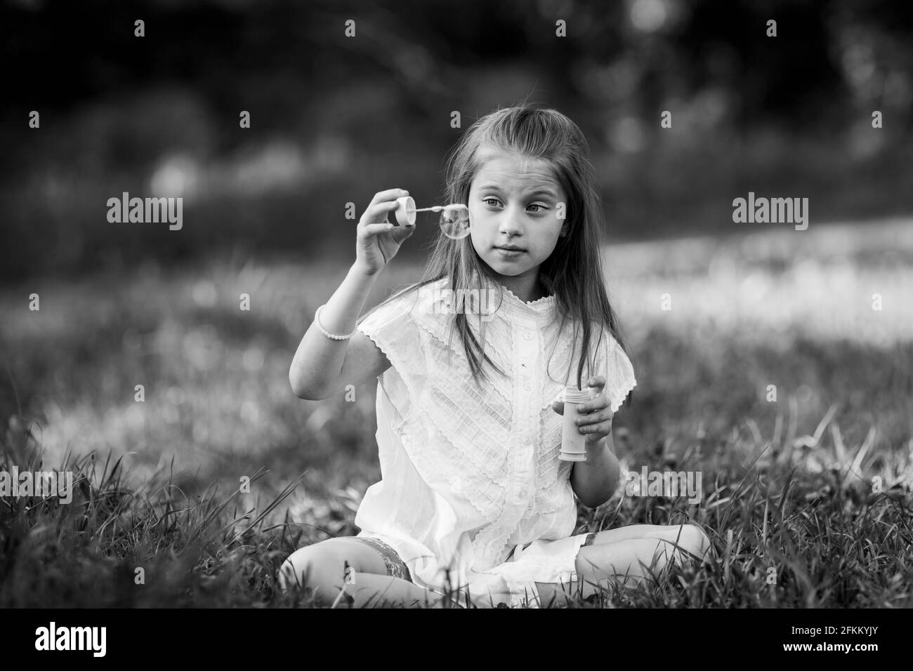 Kleines Mädchen und Seife Blasen im Freien. Schwarzweiß-Foto. Stockfoto