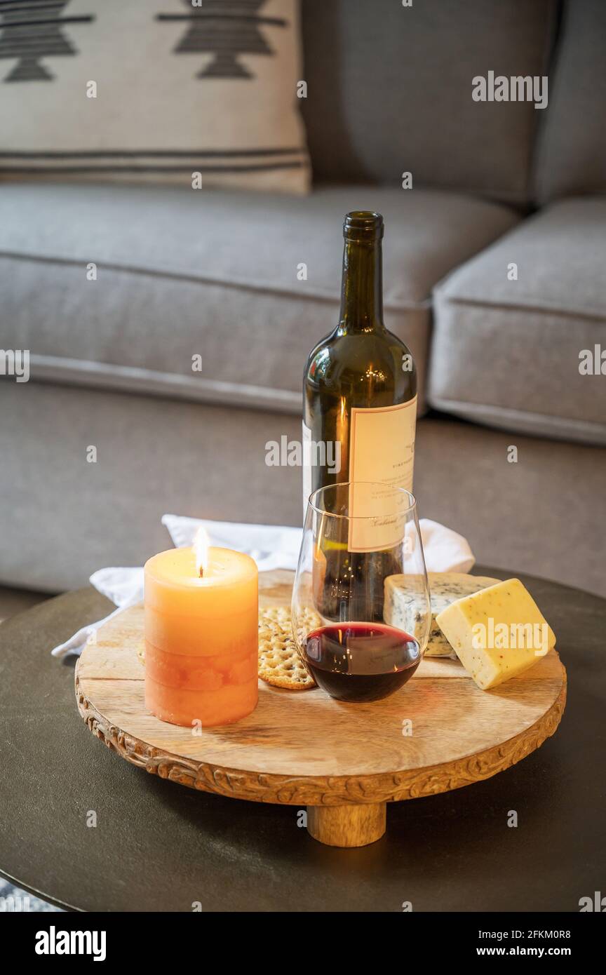 Eine Käseplatte mit Wein, Käse, Crackern und einer brennenden Kerze in einem Hotelzimmer. Stockfoto