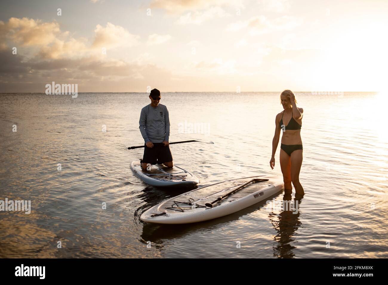 Zwei Menschen in Hawaii kommen nach dem Paddleboarding zurück zum Strand Stockfoto