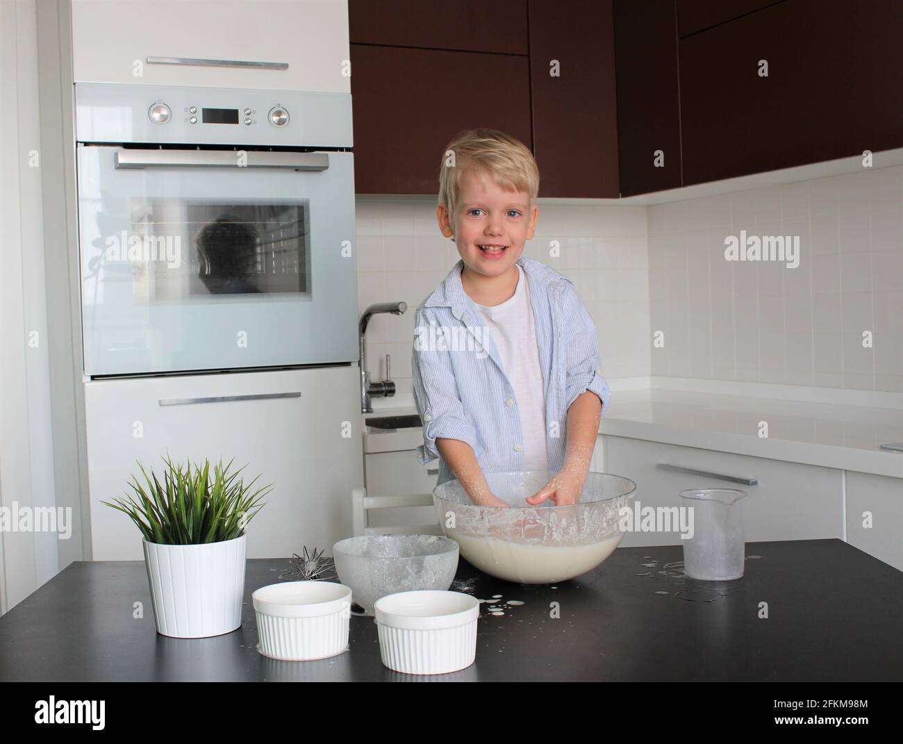 Ein 3-jähriges Kind kocht in einer weißen Küche Stockfoto