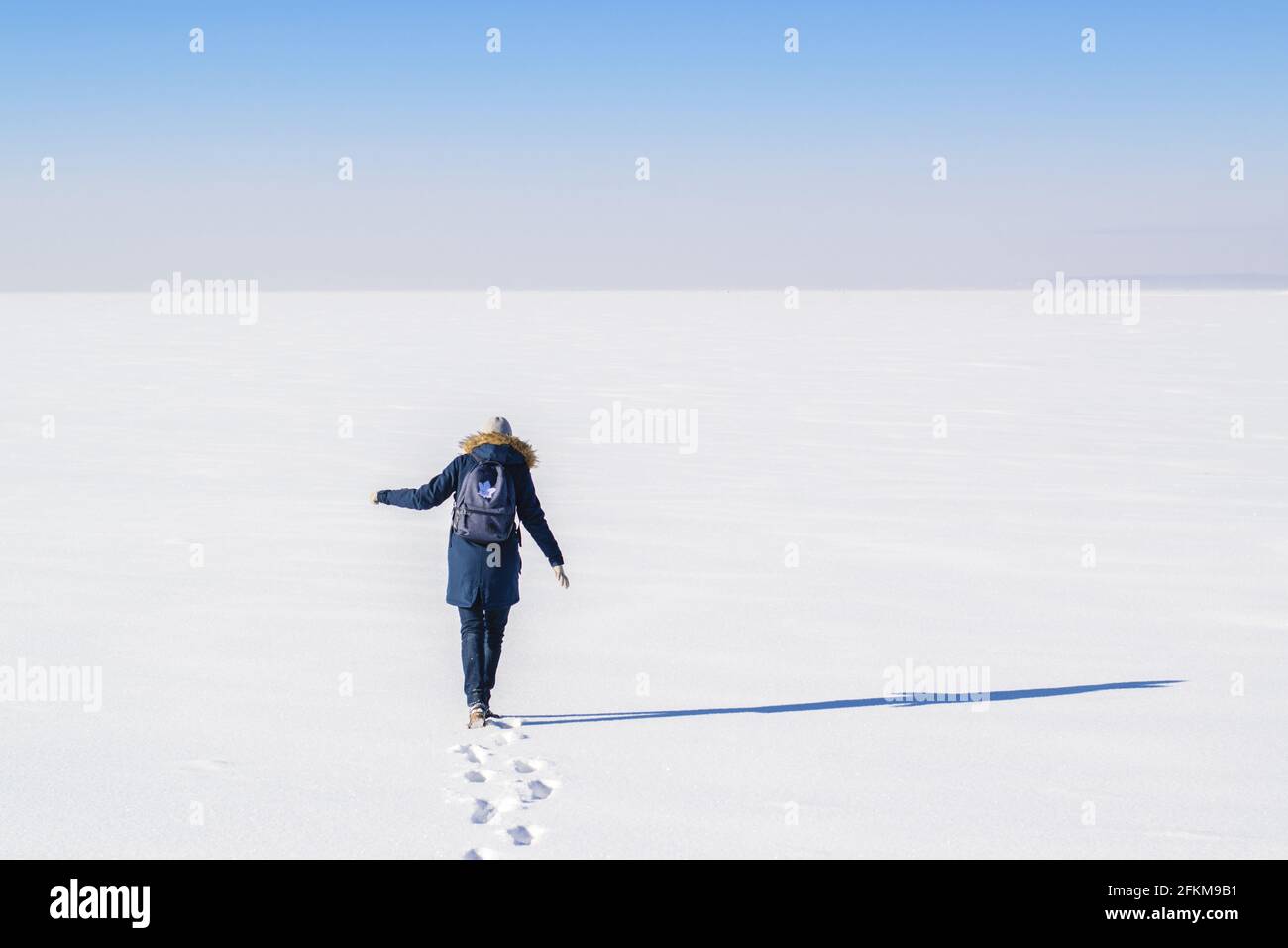 Frau in blauem Mantel, die auf Schnee läuft Stockfoto