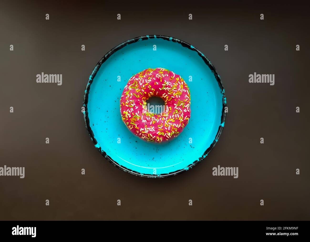 Rosa Donut auf blauem Teller, Draufsicht Stockfoto