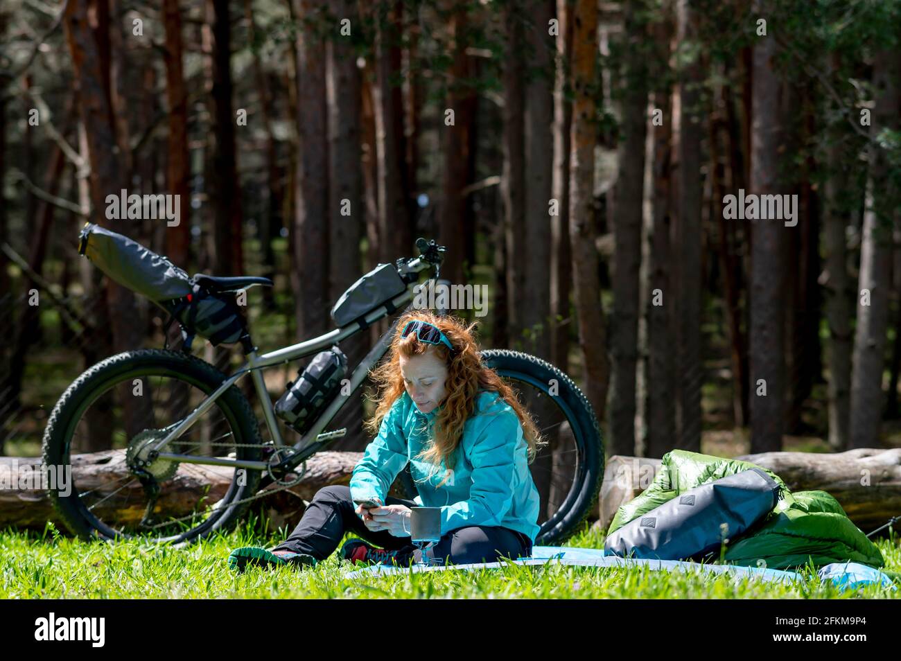 Eine Frau, die neben ihrem Abenteuer ein Handy benutzt Fahrrad Stockfoto