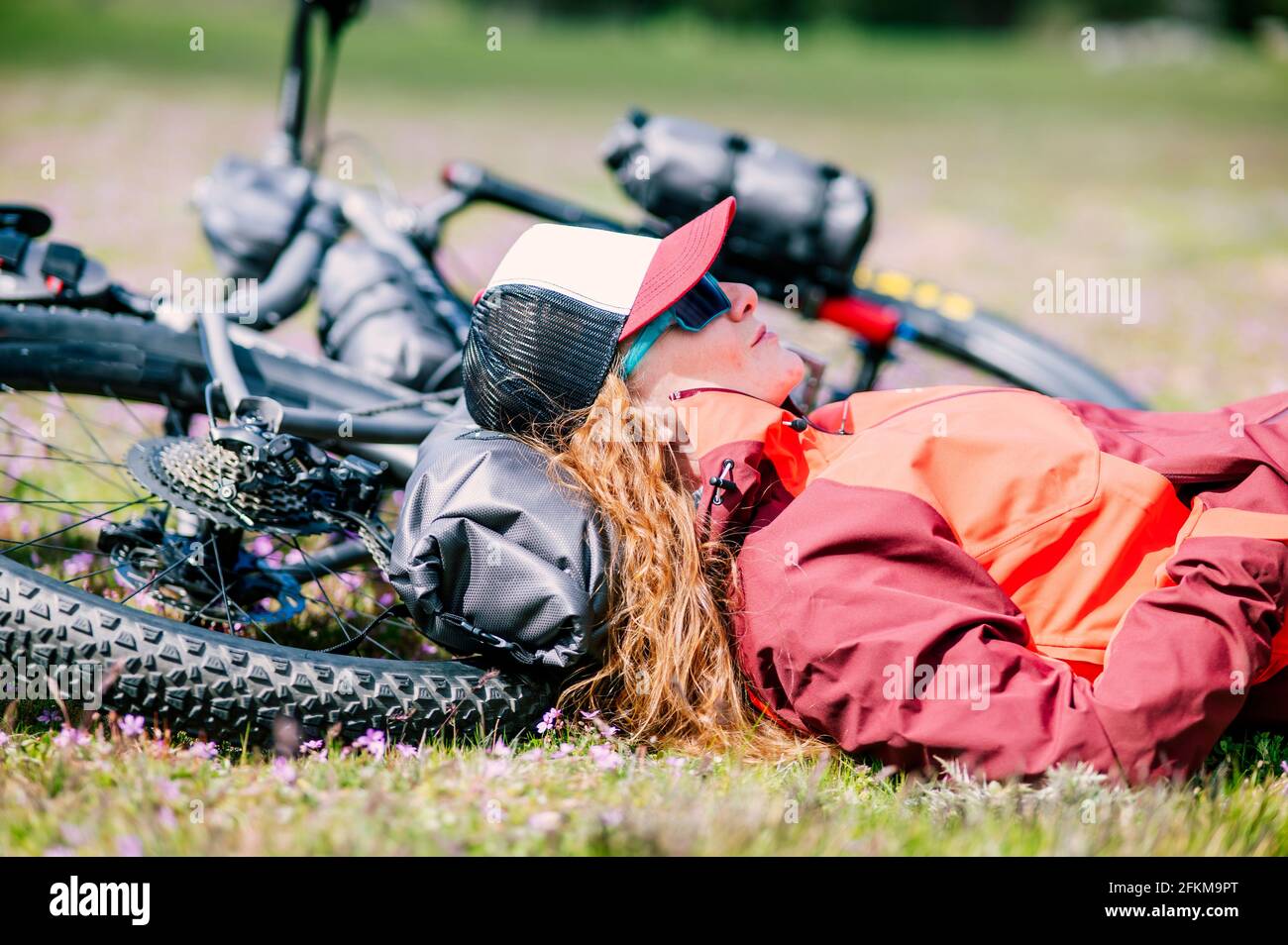 Eine Frau, die auf ihrem Mountainbike in einem Grün liegt Wiese im Frühling Stockfoto