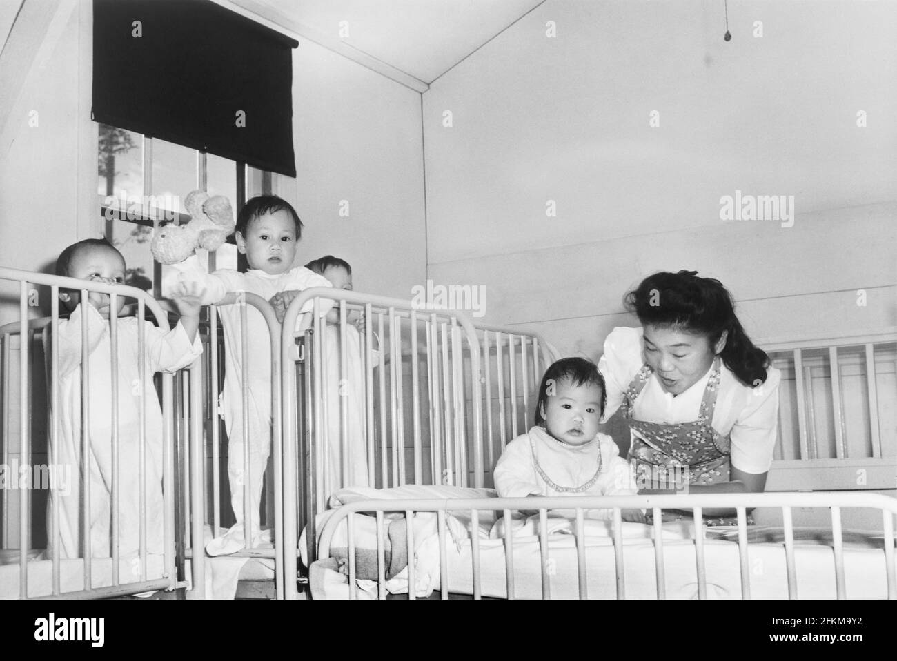 Krankenschwester, die sich um Waisenkinder im Kindergarten, Manzanar Relocation Center, Kalifornien, USA, Ansel Adams, Manzanar War Relocation Center Collection, 1943 Stockfoto