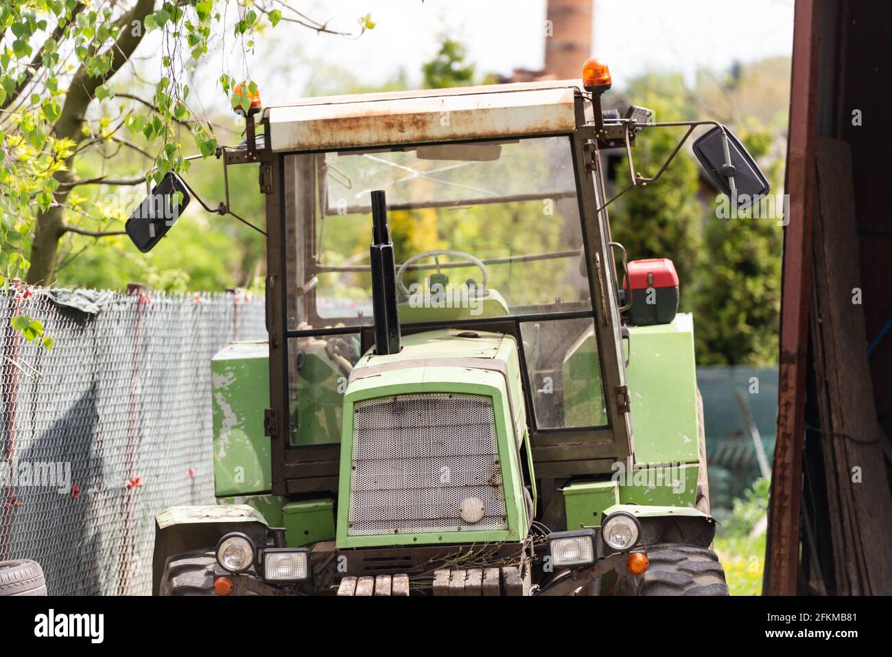 Alter Traktor in der Scheune. Ein alter Traktor steht in der Nähe von Scheune und Zaun. Stockfoto