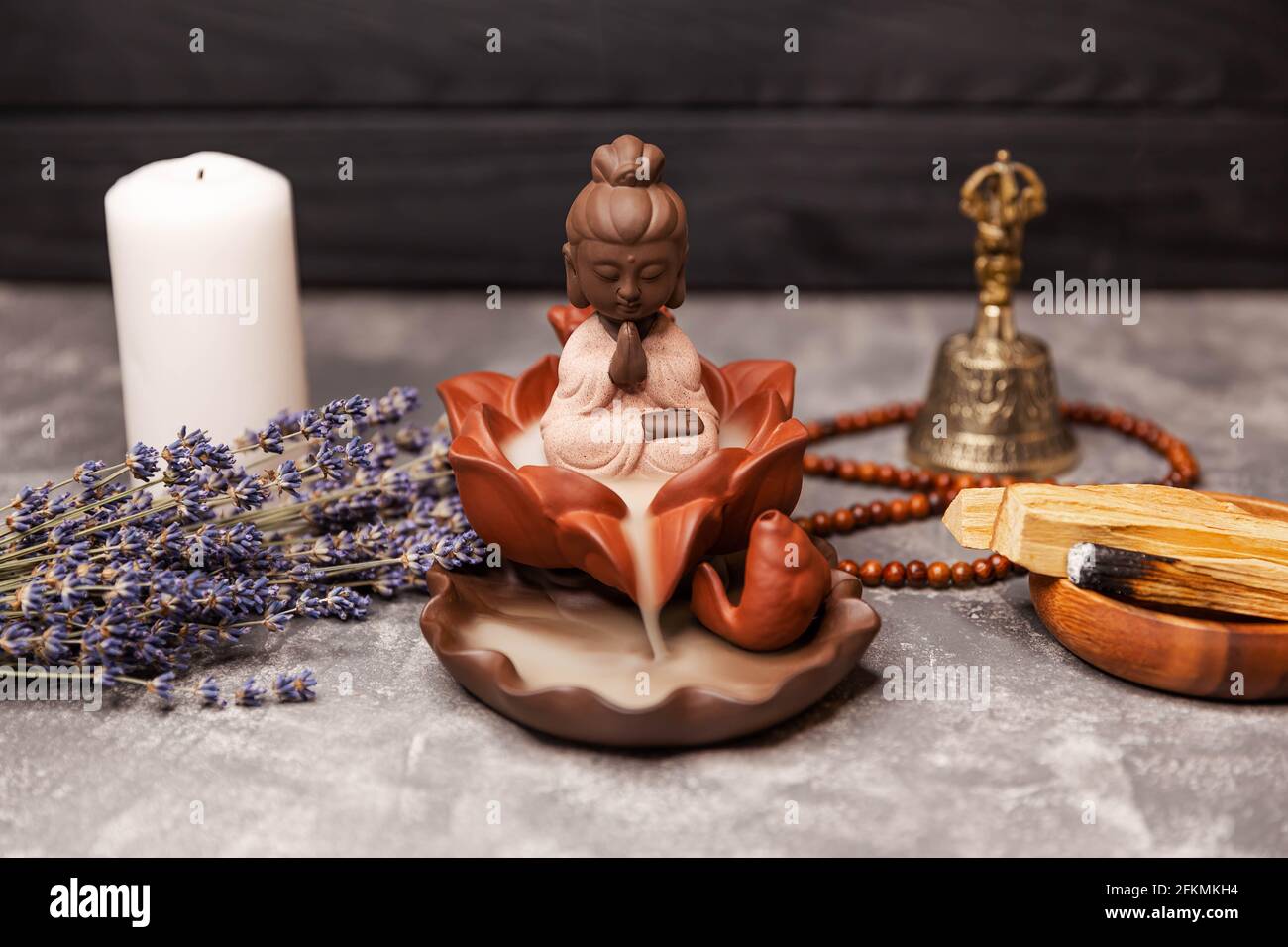 Buddha-Statue mit Kerzenbrand und Räucherrauch. Aromatherapie Stockfoto