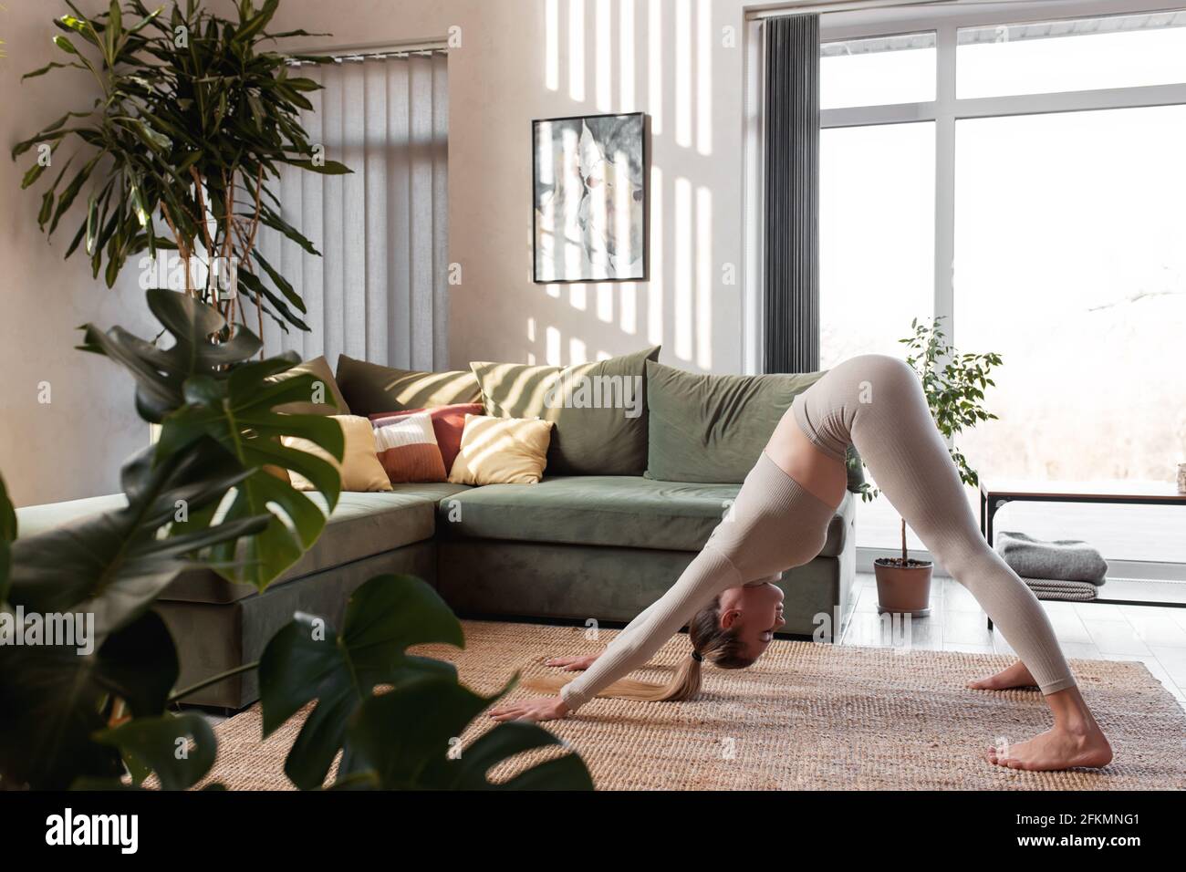 Gesundes Lifestyle-Konzept mit Mädchen tun Yoga-Übungen zu Hause Mit grünem Loft-Innenraum Stockfoto