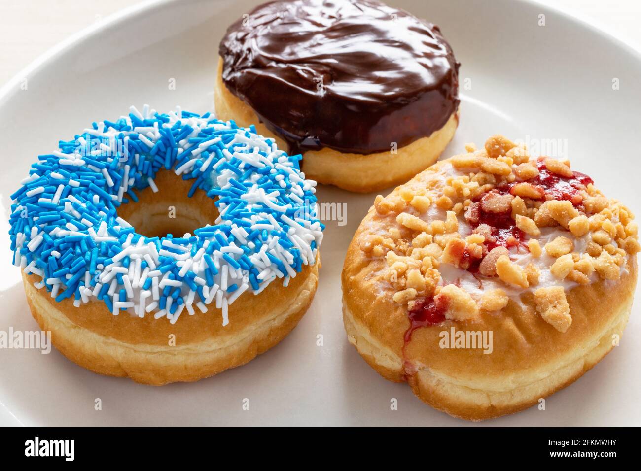 Donuts mit verschiedenen Belägen auf weißem Teller. Stockfoto