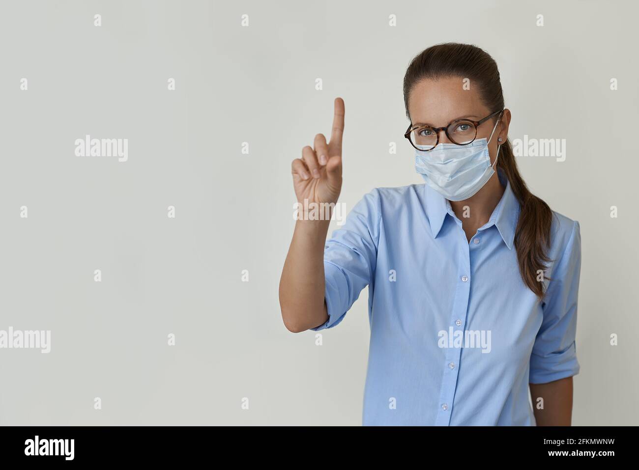 Frau in medizinischer Maske zeigt ihren Finger Stockfoto