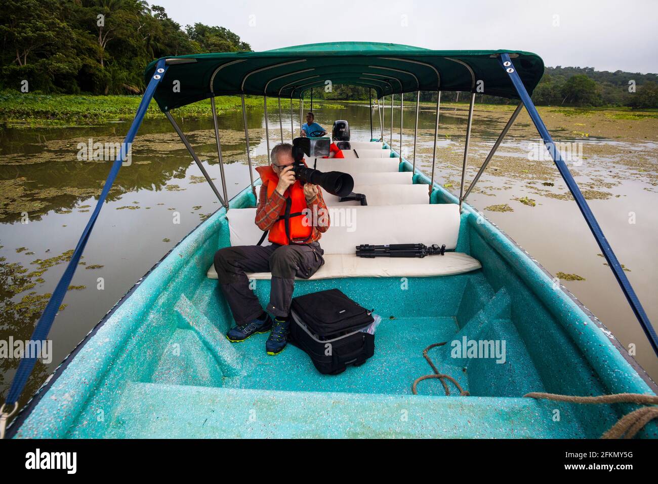 Ein Tourist mit Teleobjektiv fotografiert Wildtiere von einem Boot aus in einem der Seitenarme des Gatun Sees, Provinz Colon, Republik Panama. Stockfoto