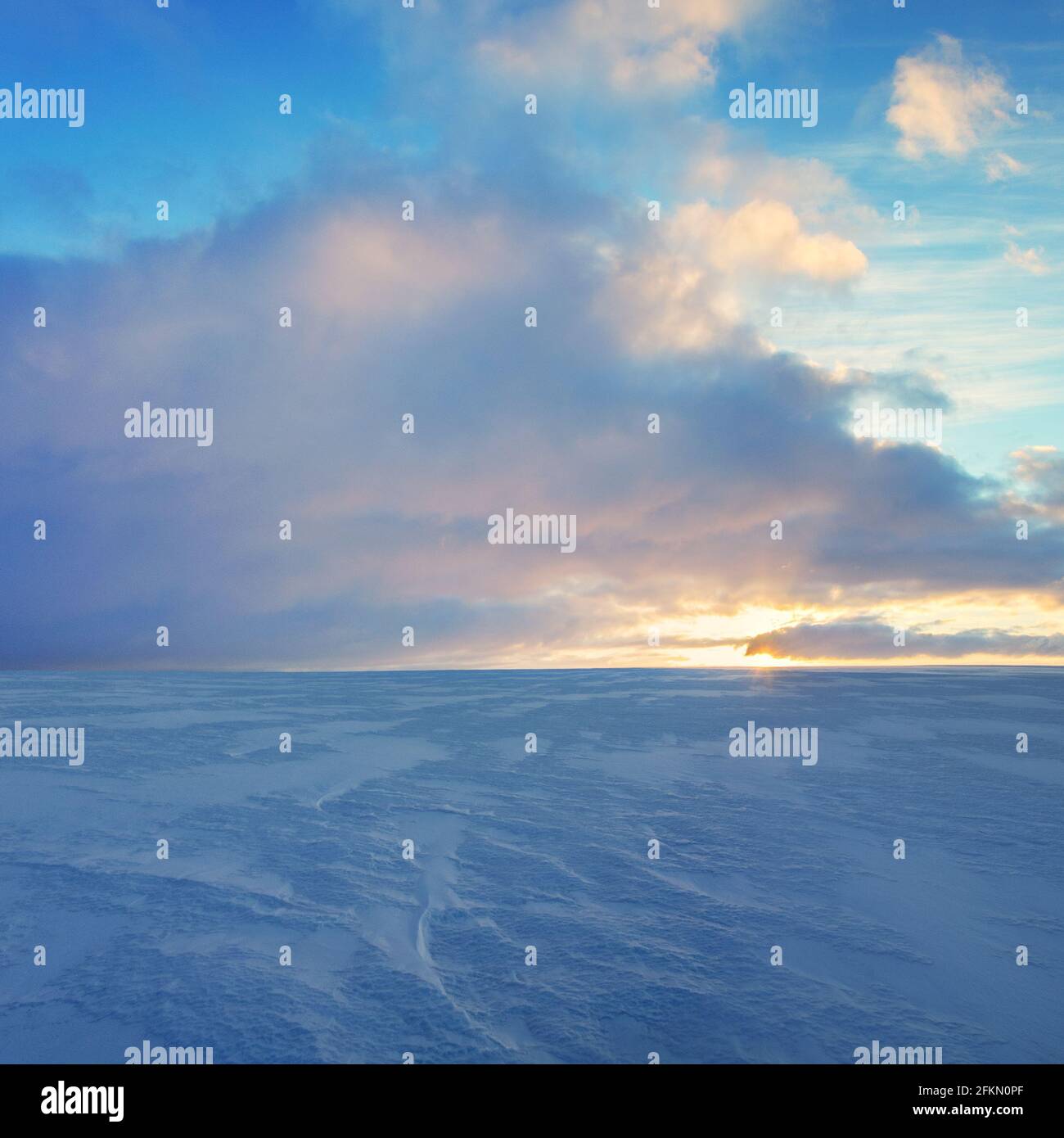 Wunderschöne Panoramalandschaft mit dramatischen Wolken am blauen Himmel über dem schneebedeckten Feld.Sonnenaufgang Landschaft. Stockfoto