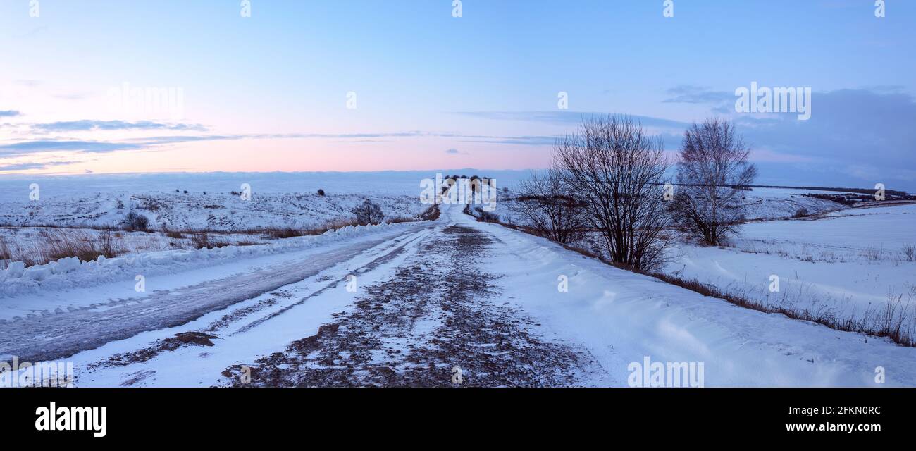 Winterlandschaft mit Boden ländlichen Straße durch Felder an sonnenaufgang Stockfoto