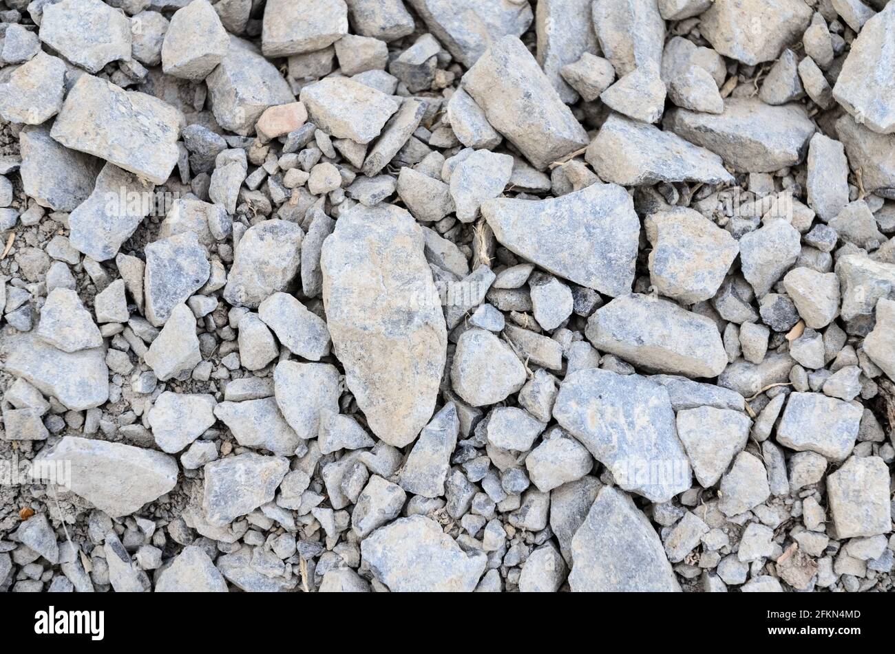 Abstrakter Hintergrund mit zerkleinertem Kies und kleinen grauen Felsen und Steinen, Nahaufnahme von direkt oben Stockfoto