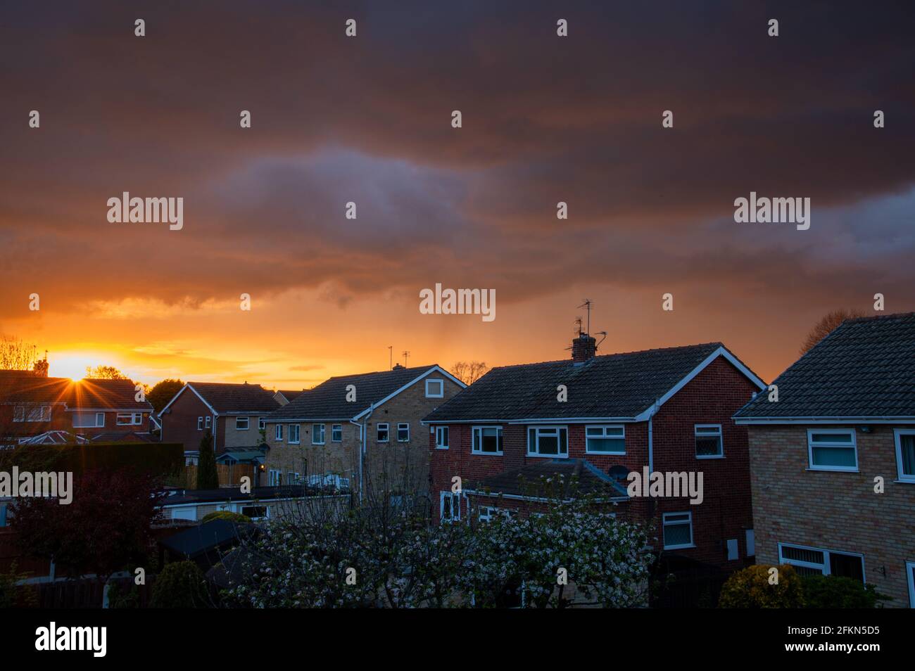 Stürmischer Sonnenuntergang über einem Wohngebiet Stockfoto