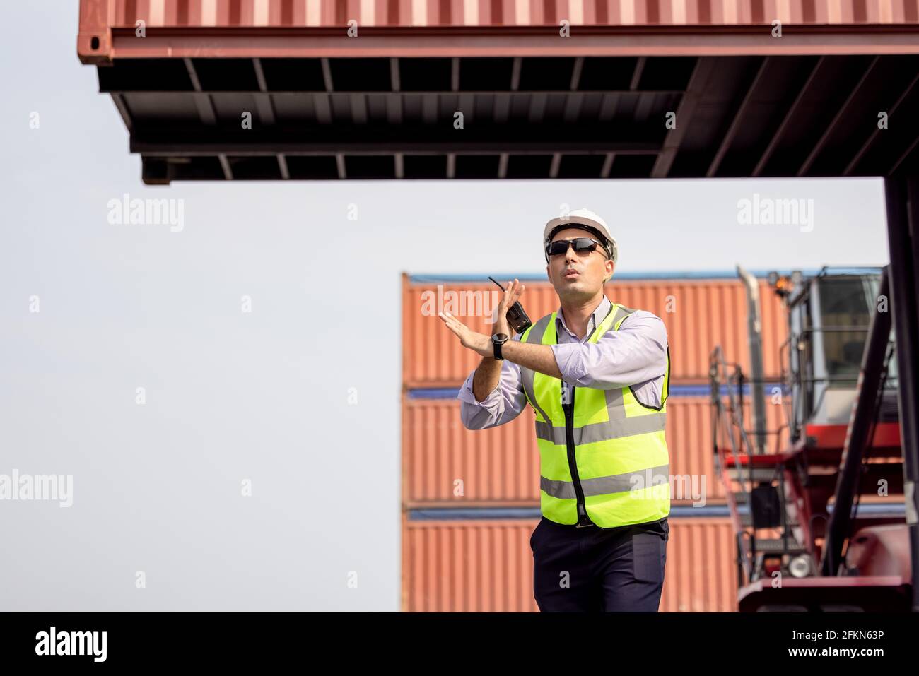 Mann mit Walkie Talkie am Container Terminal kontrolliert Industriearbeiter die Containerverladung Stockfoto
