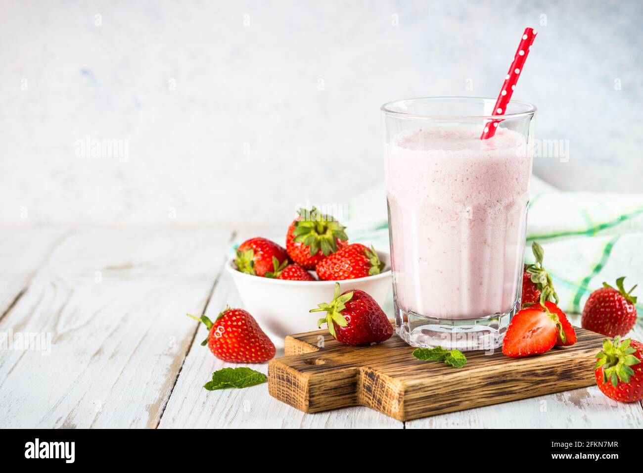 Erdbeer-Smoothie oder Milchshake am weißen Tisch. Stockfoto