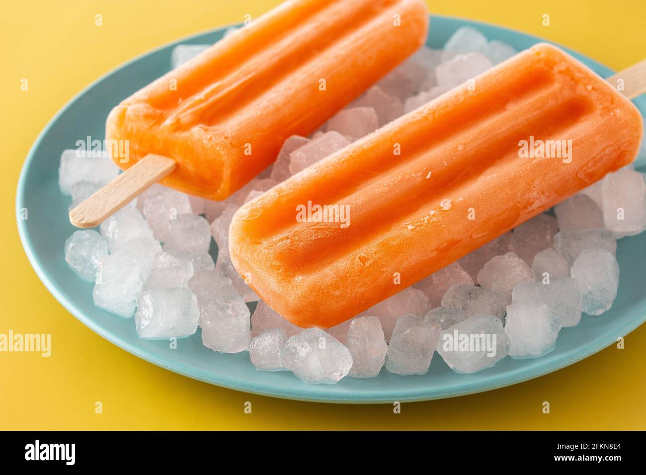 Orangefarbene Eiszapfen auf gelbem Hintergrund Stockfoto