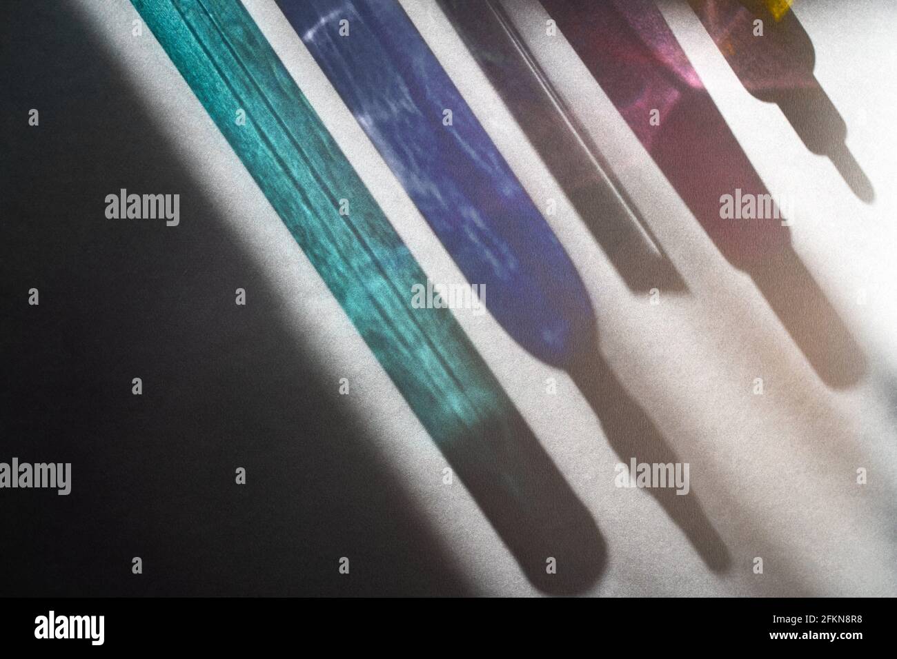 Blau türkis rosa und gelbe Glasflasche Reflexionen in rauem Licht. Beauty-Produkte in einem neuen Licht. Stockfoto