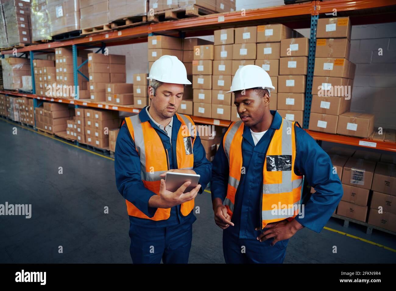 Zwei Industriearbeiter diskutieren über Projektarbeit in großen Industrieanlagen Mit digitalem Tablet Stockfoto