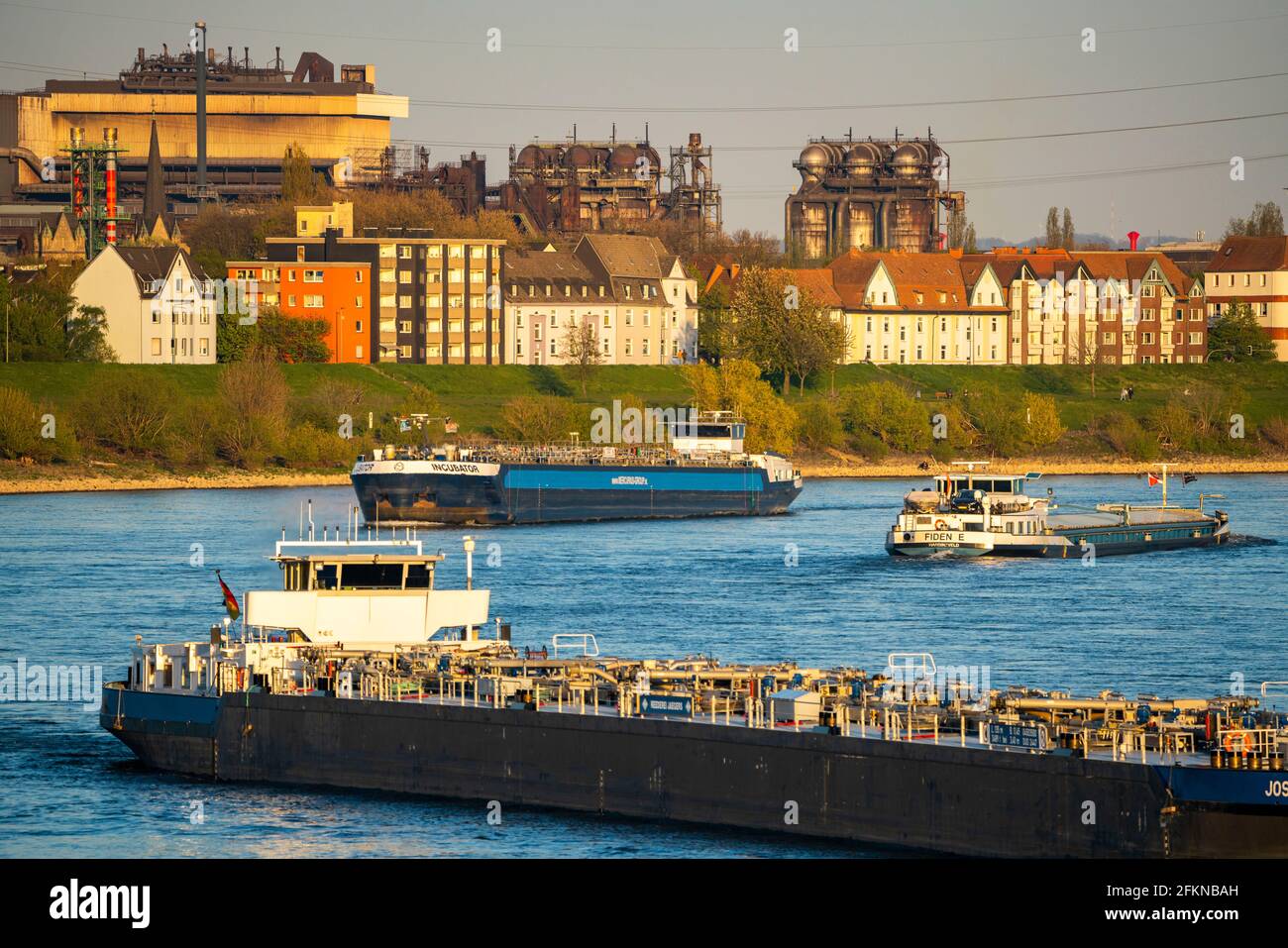 Frachtschiffe auf dem Rhein bei Duisburg-Laar, Häuser auf der Deichstraße, Industriekulisse des Stahldrahtwerks ArcelorMittal Hochfeld GmbH, NRW, Ge Stockfoto