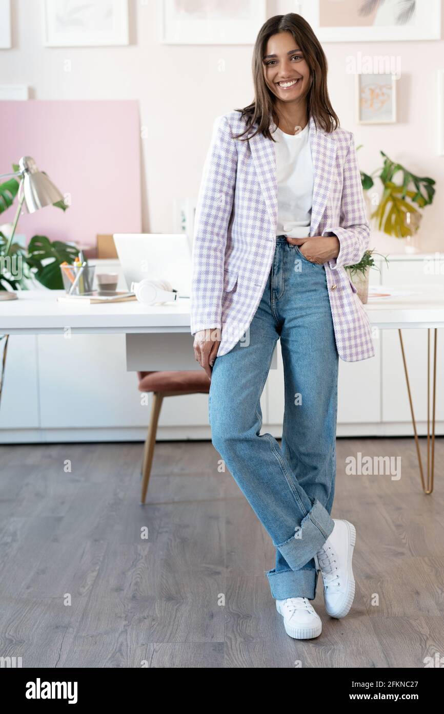 Selbstbewusste junge Frau in eleganter Freizeitkleidung lächelnd im Stehen In der Nähe ihres Arbeitsort Stockfoto
