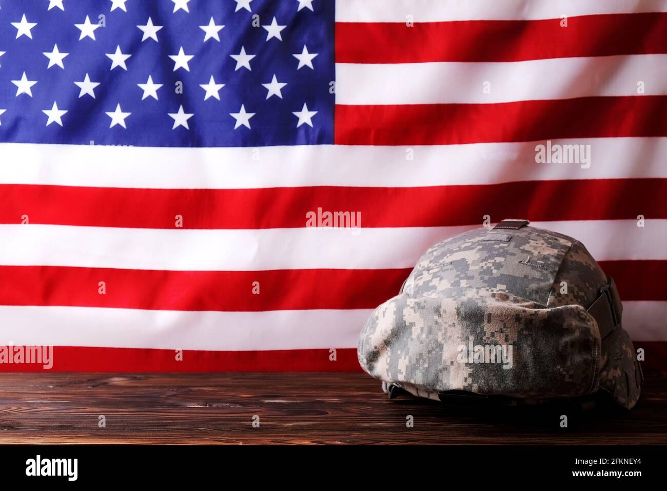 US Army Kevlar Kampfhelm, Camoabdeckung, taktische Brille, USA Flagge Hintergrund. Memorial Weekend, Veteranentag, United States of America Armed Forces Stockfoto