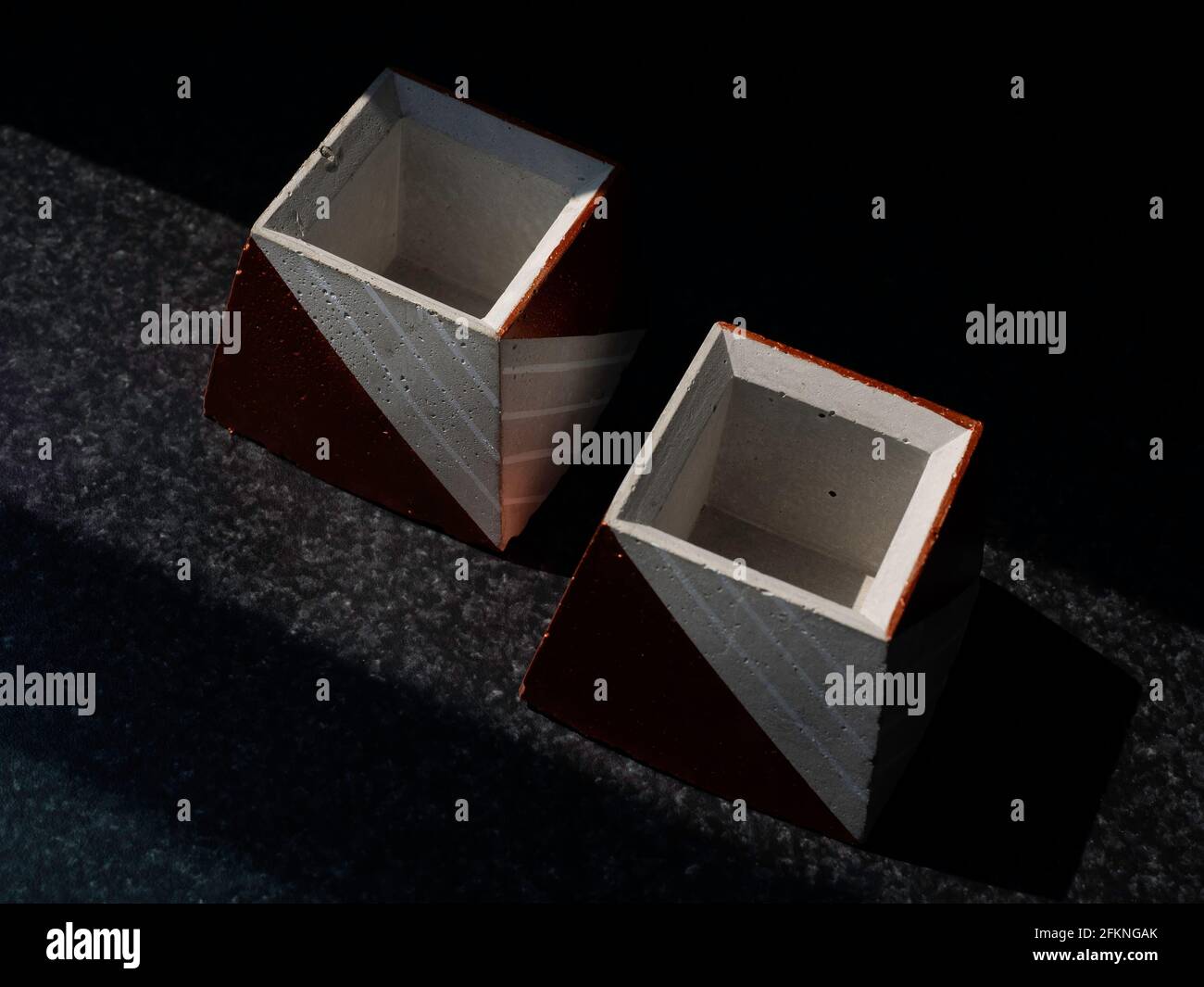Leere DIY Betontöpfe, Pyramidenform auf dunklem Hintergrund, Draufsicht. Zwei einzigartige kupferfarben lackierte Zementpflanzer. Stockfoto