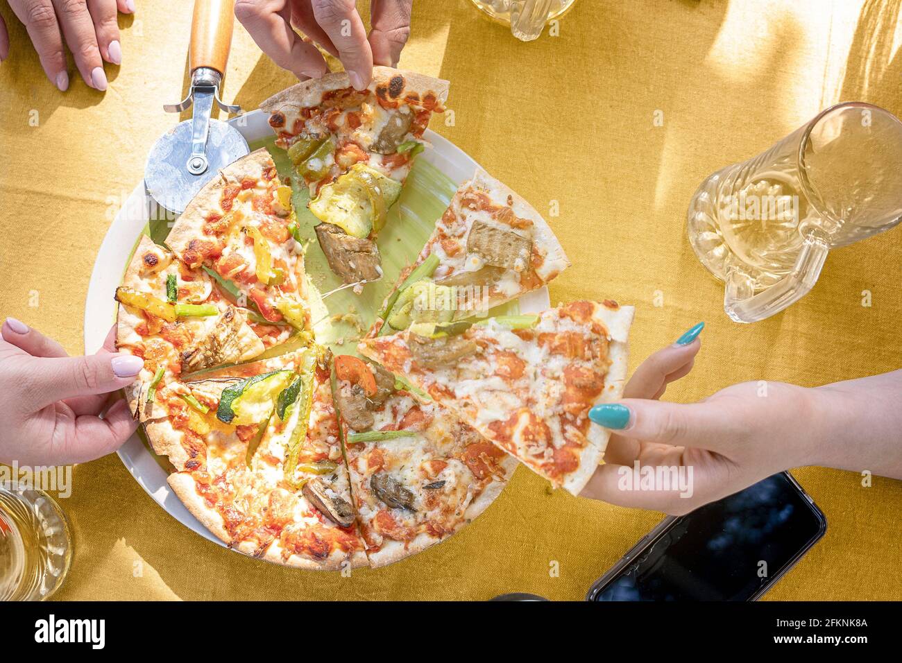 Schneiden Pizza auf dem Tisch mit Freunden geteilt. Freizeit feiern mit italienischem Essen Stockfoto