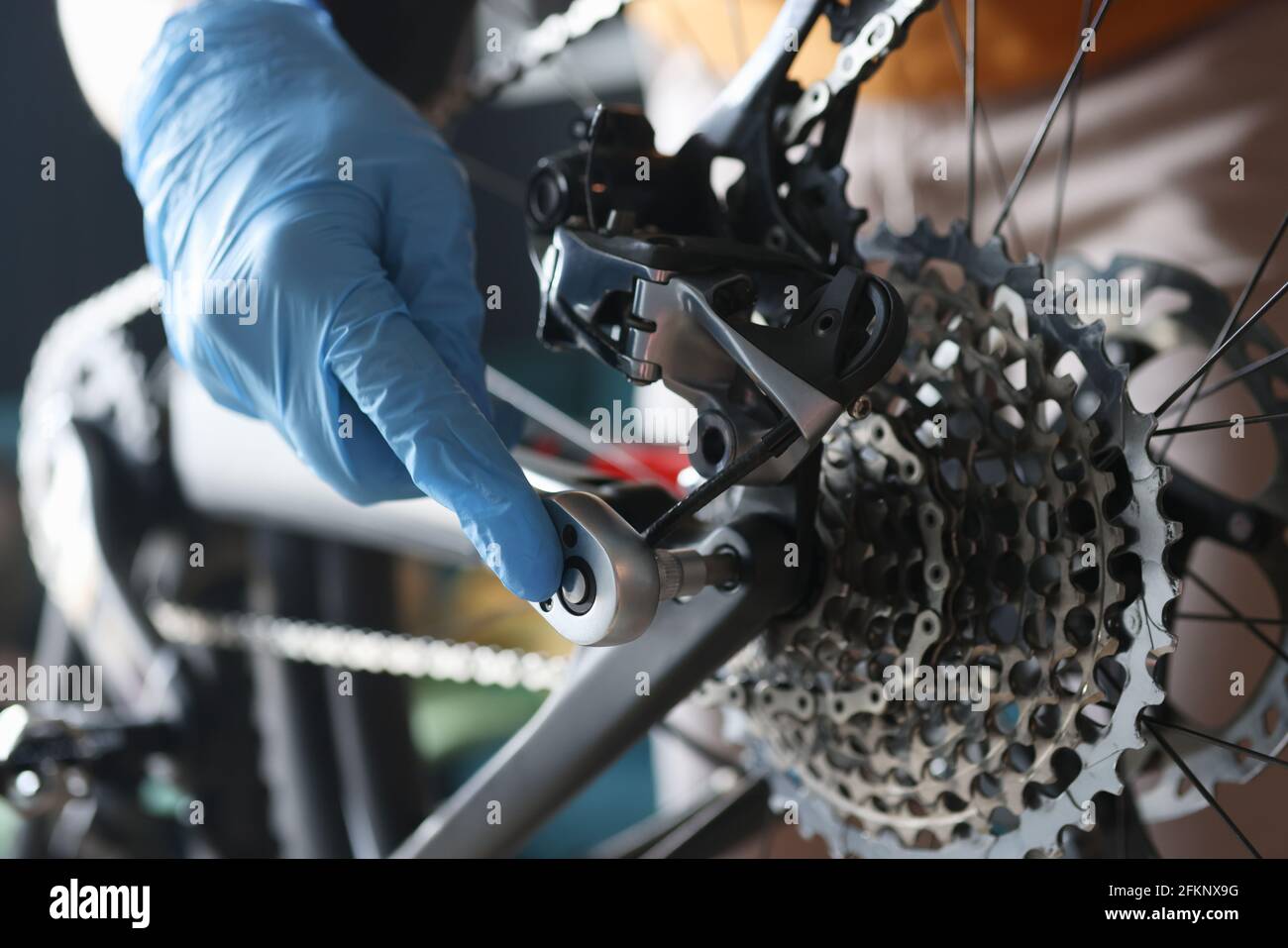 Handwerker in Gummihandschuhen Reparatur Fahrrad in der Werkstatt Nahaufnahme Stockfoto