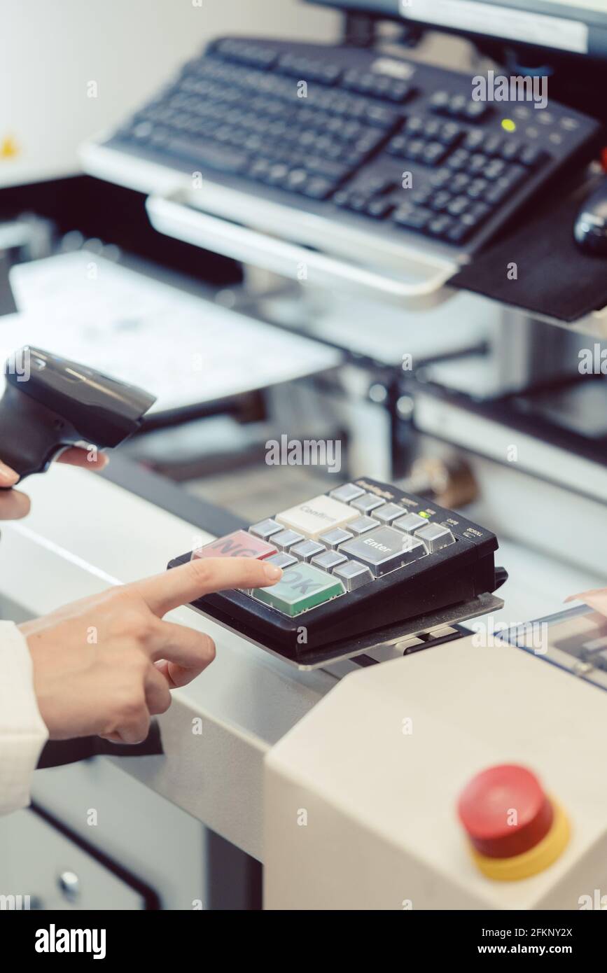 Fabrikarbeiter, der an einer Maschine die OK-Taste drückt Stockfoto