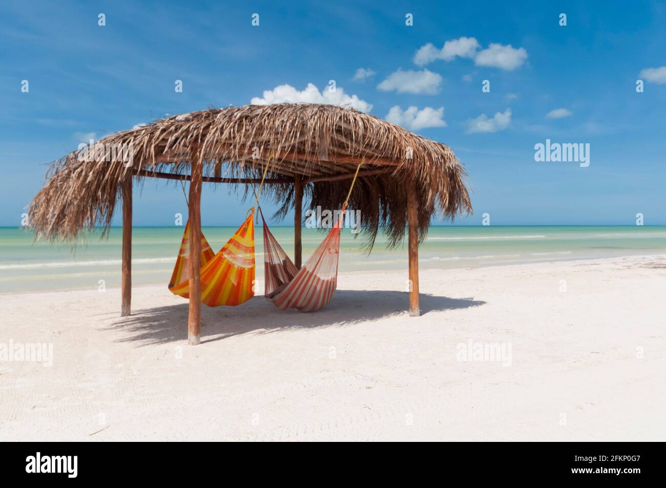 Eine rustikale Hütte mit Hängematten an einem Strand auf Holbox Island in Mexiko, im Hintergrund der blaue Himmel und der Karibische Ozean. Entspannungsreisekonzept Stockfoto