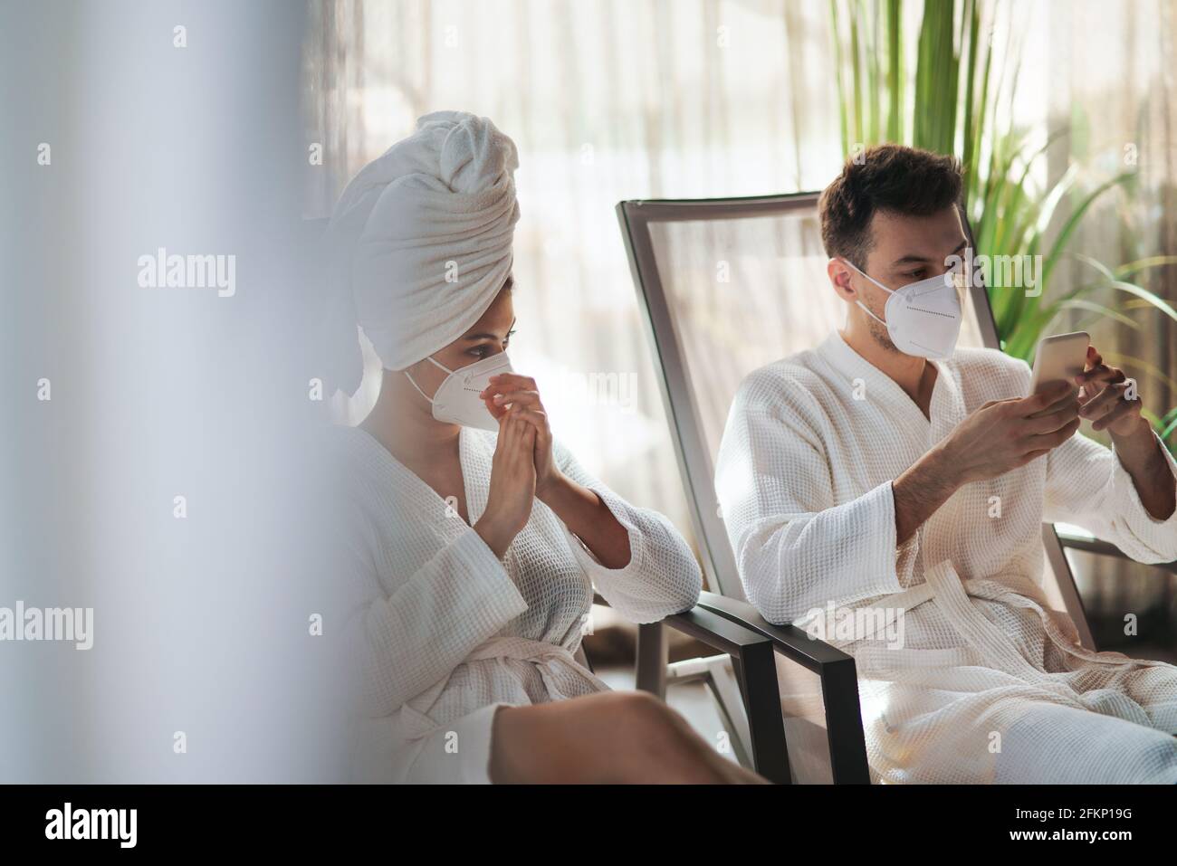 Junges Paar, das im Spa-Resort sitzt und sich entspannt, Coronavirus-Konzept. Stockfoto