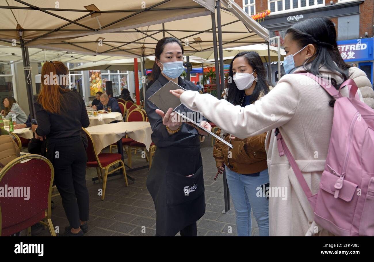 London, England, Großbritannien. Chinatown – Touristen, die während der COVID-Beschränkungen vor einem Restaurant in der Gerrard Street ein Menü überprüfen. April 2021 Stockfoto