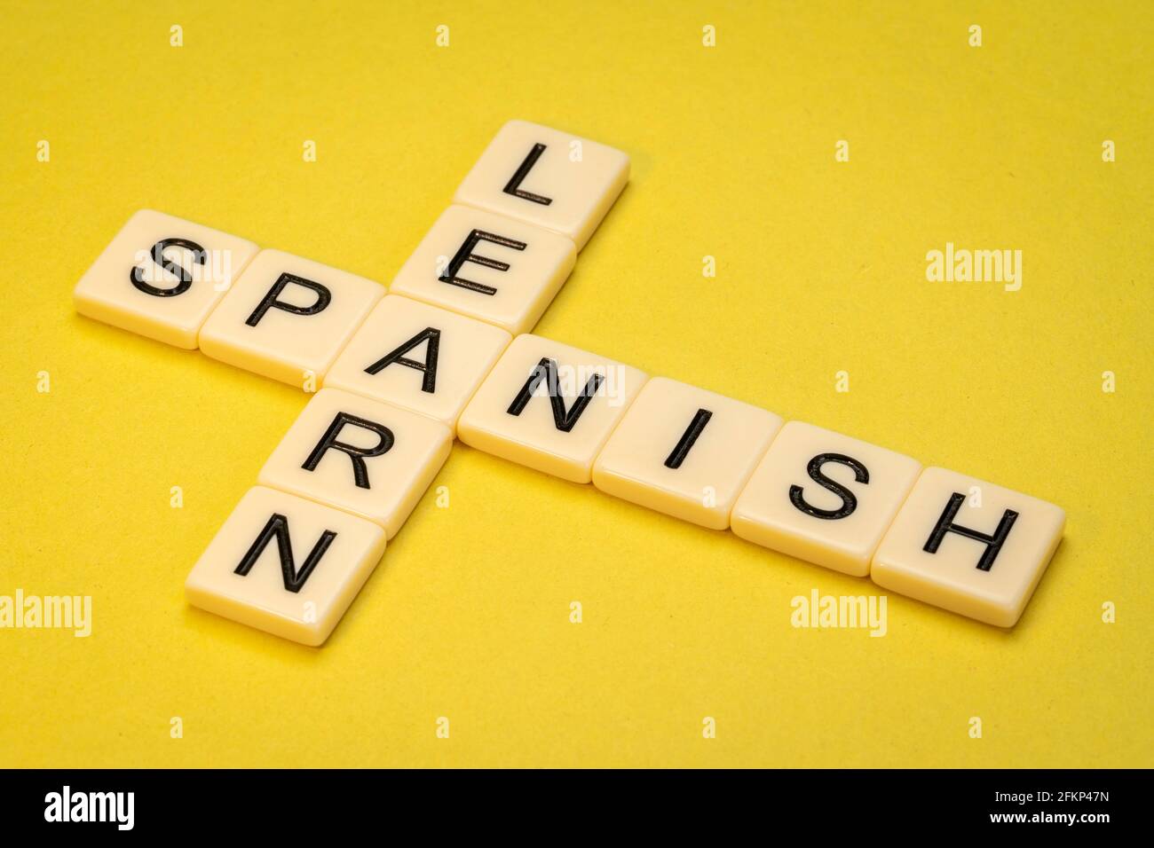 Spanisch lernen Kreuzworträtsel in Elfenbein Buchstaben Fliesen gegen gelb strukturiert Papier Stockfoto