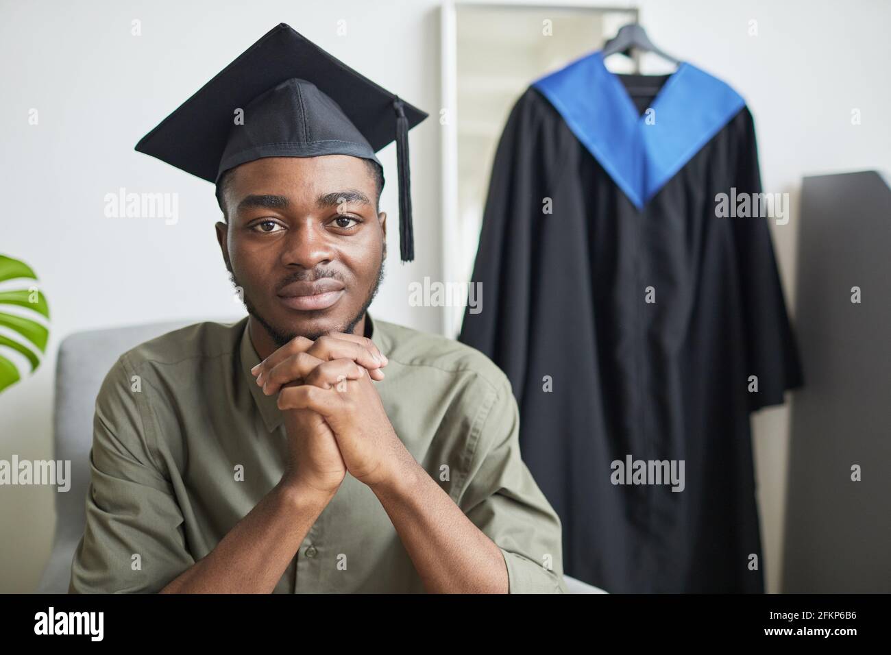 Porträt eines jungen afroamerikanischen Mannes, der während der Vorbereitung auf die Kamera schaut Für die Abschlussfeier im Innenbereich Stockfoto