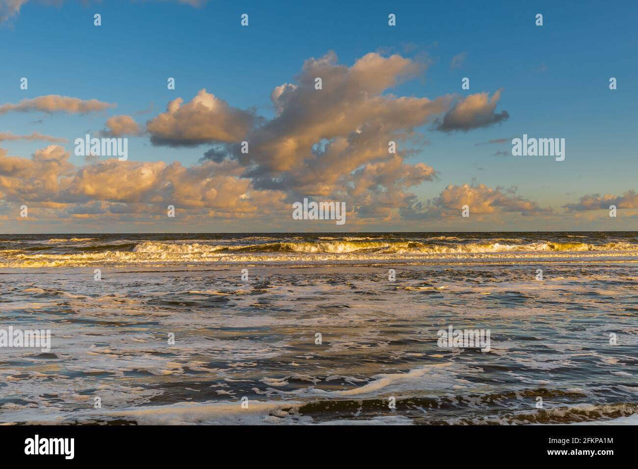 Sonnenaufgang Nordseestrand der Niederlande mit gelber Brandung Und Wellen und schaumiges Meerwasser bei Flut Vor dem Hintergrund von warmen Farben Stockfoto