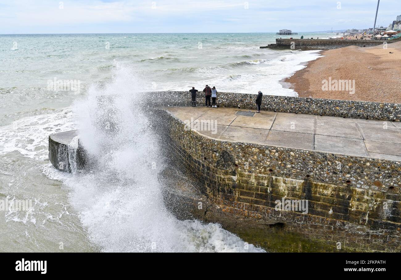 Brighton UK 3. Mai 2021 - Wellen stürzen an die Strandpromenade von Brighton, während Besucher trotz des windigen Wetters die Feiertage im Mai genießen : Credit Simon Dack / Alamy Live News Stockfoto