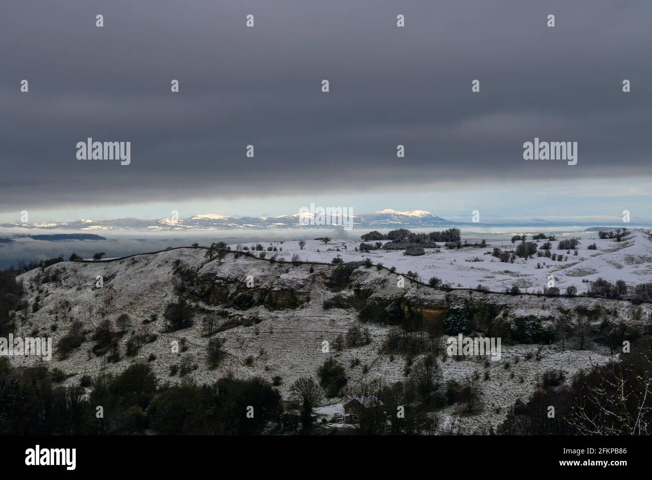 Birdlip, Cotwolds, Gloucestershire, Großbritannien mit Schnee im April mit Malvern Hills in der Ferne. Blick über das Avon Valley. Stockfoto