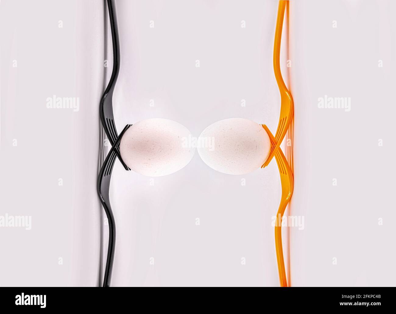 Zwei schwarze Gabeln und zwei orangefarbene Gabeln mit Eiern. Konzept inklusive Teamwork Stockfoto