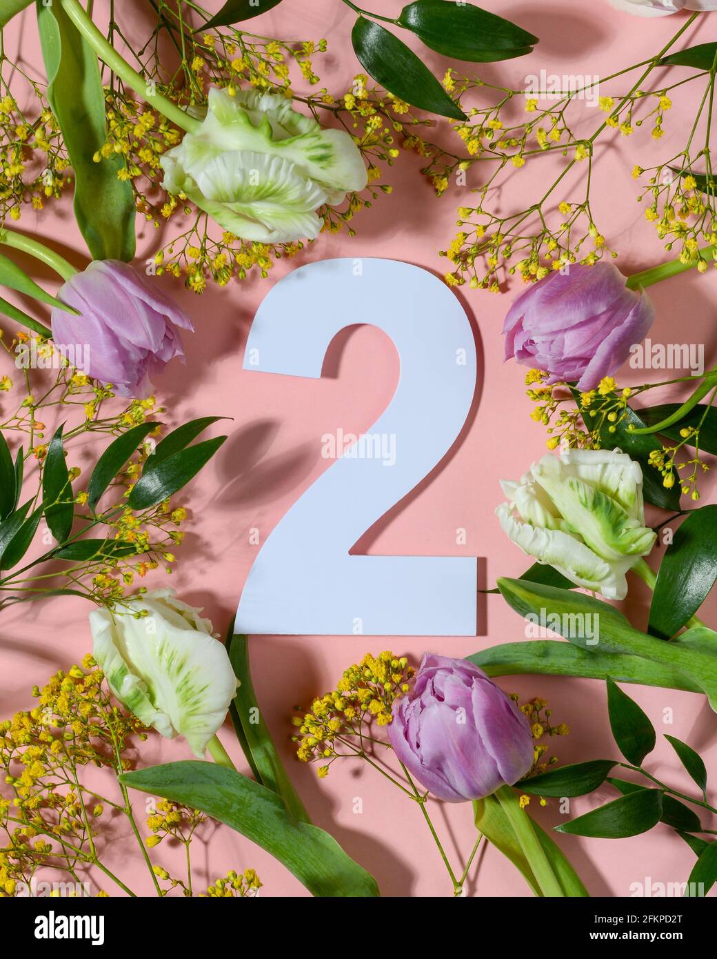 Nummer zwei auf rosa Hintergrund mit bunten Blumen. Flach liegend, Draufsicht. Stockfoto