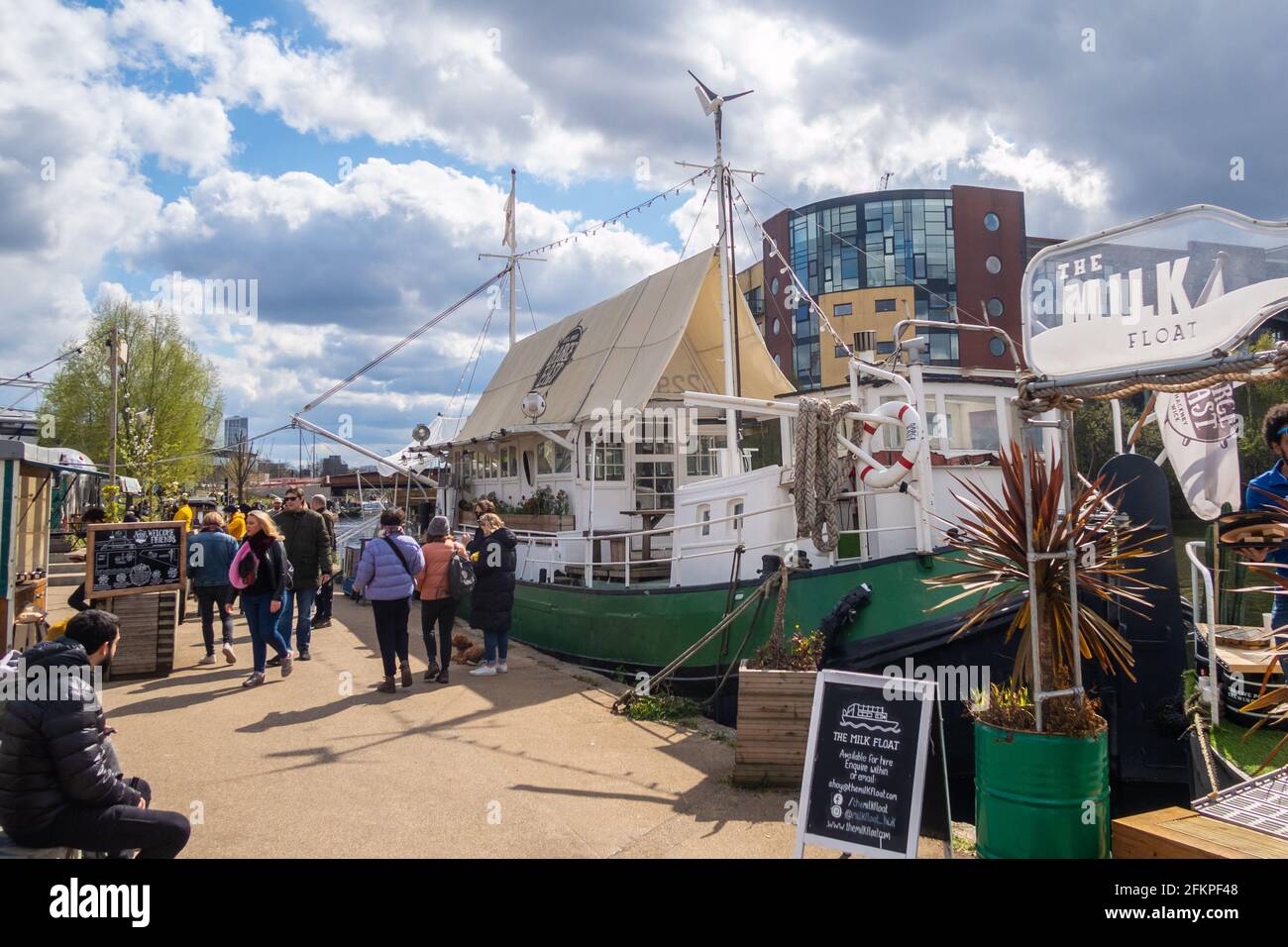 LONDON, Großbritannien - 11. APRIL 2021: Menschen vor den Grachtenbooten in Hackney Wick in London an einem sonnigen Tag. Stockfoto